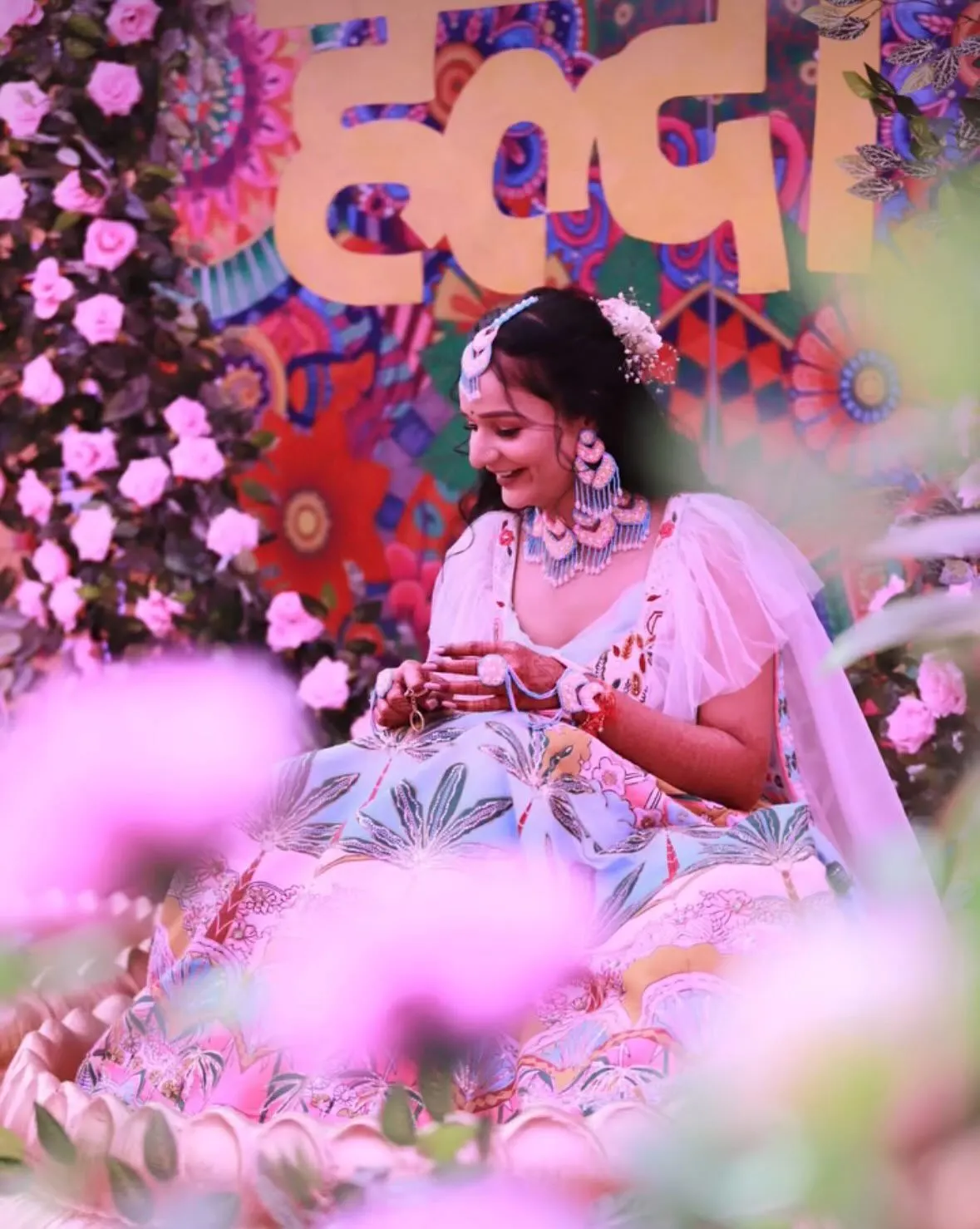 Bride at her haldi among pink flowers, floral jewellery