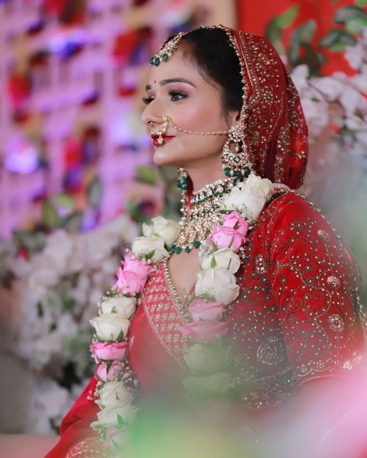 Bride in red with nath and varmala, in profile
