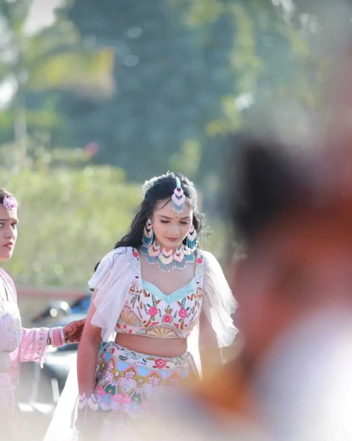 Bride walking in a pastel lehenga with floral jewellery