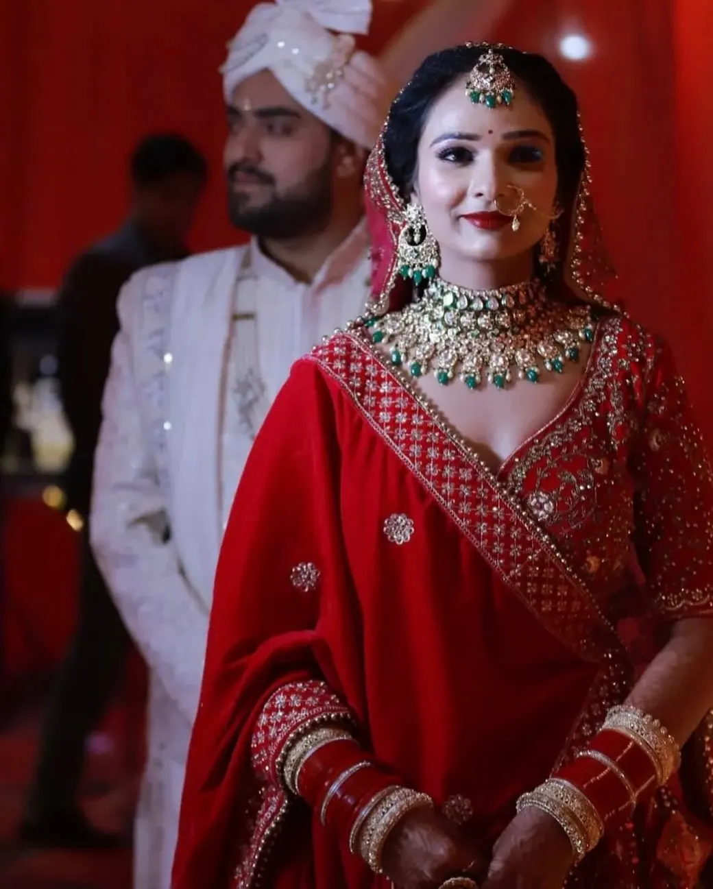Bride in a red lehenga with polki necklace and maang tikka